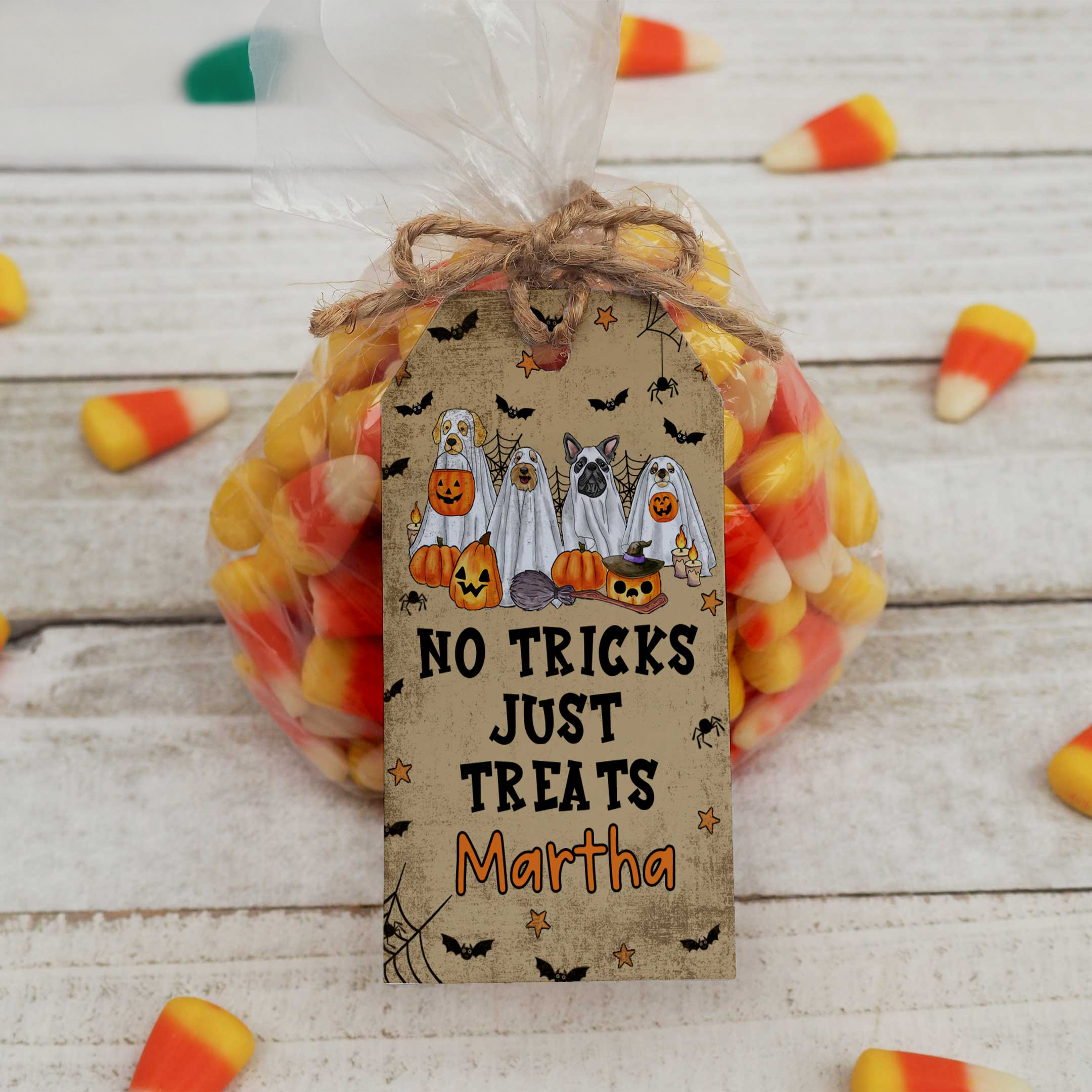 Halloween-themed gift bag with candy corn and a personalized tag on a wooden surface.