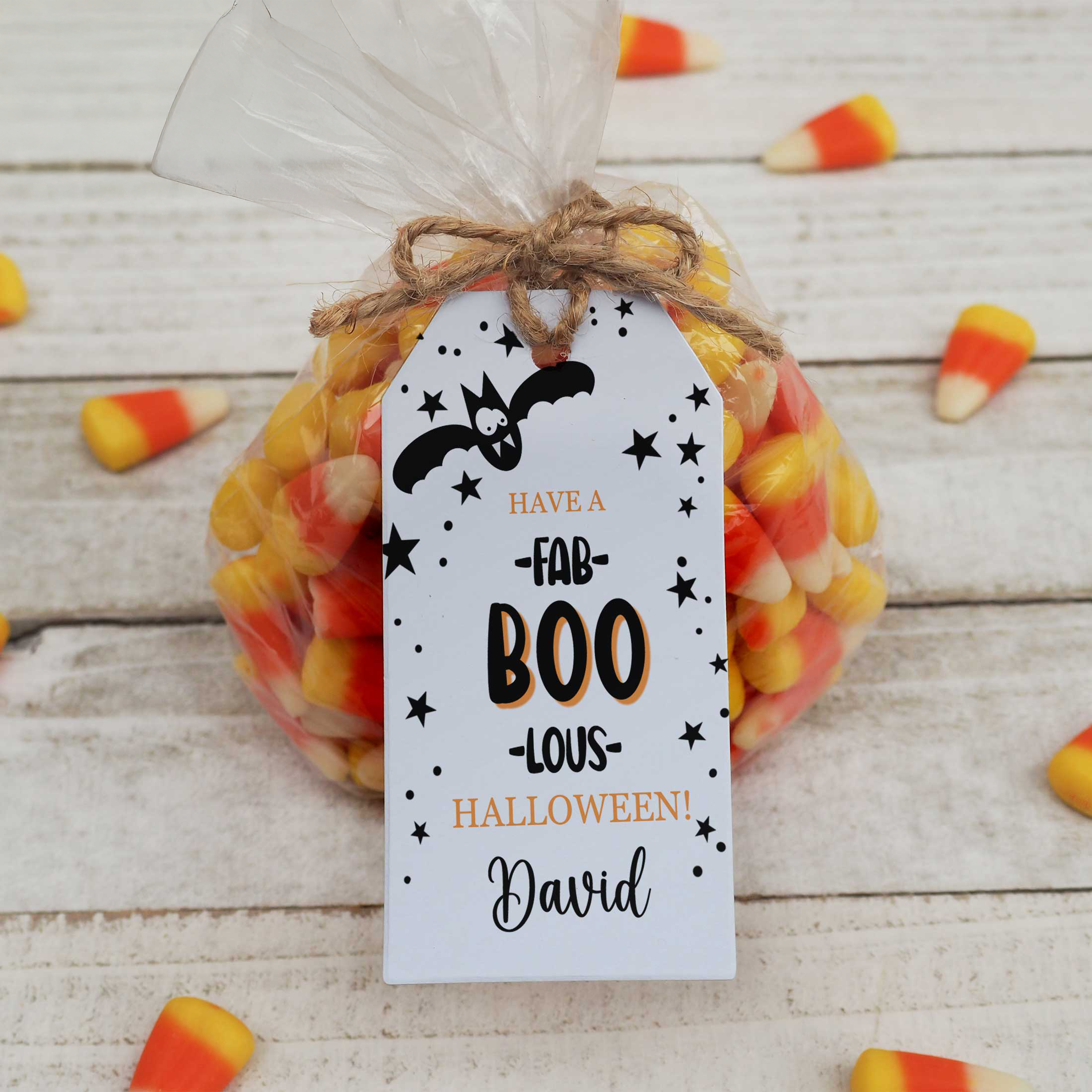 Halloween-themed candy bag with a personalized tag on a wooden surface.