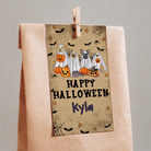 Halloween-themed towel with cartoon dogs dressed as ghosts and pumpkins, hanging on a wooden peg against a gray background.