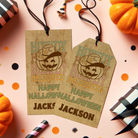 Two Halloween-themed gift tags with pumpkins and ribbons on a pink background